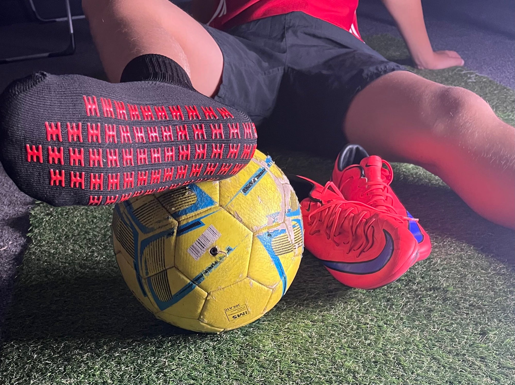 black grip sock on foot resting on yellow football